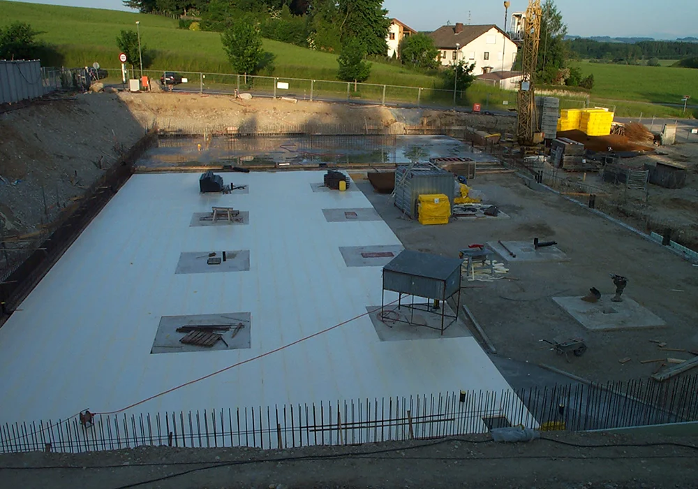 Große Baugrube mit vorbereiteter Bodenplatte für Gewerbebau auf Baustelle