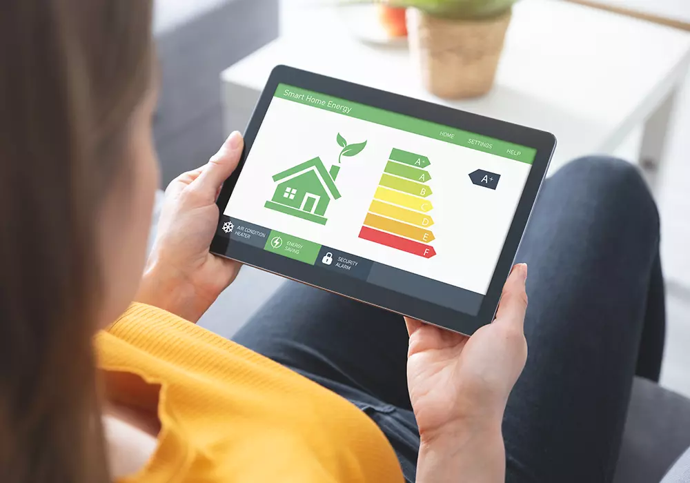 Frau hält Tablet mit Anzeige zur Energieeffizienz eines Hauses, bewertet mit A+.