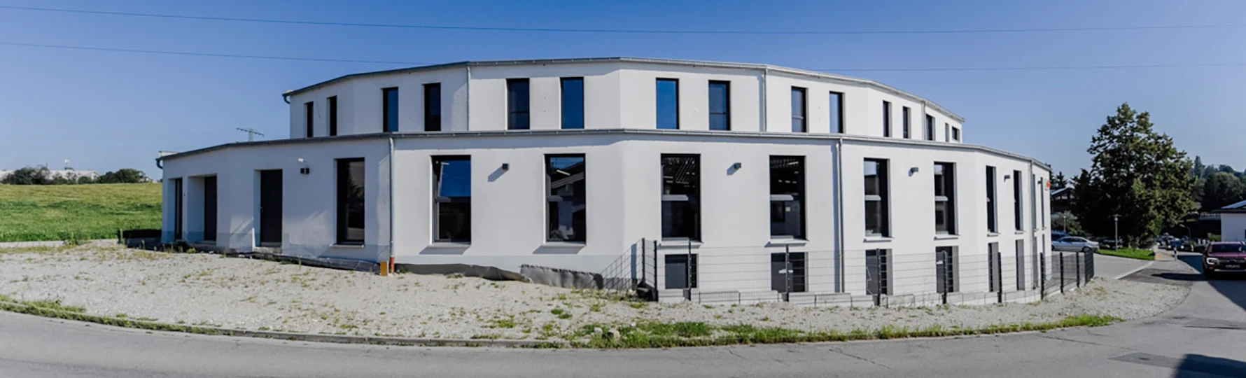 Panoramaansicht eines zweigeschossigen Gewerbegebäudes mit großen Fensterflächen