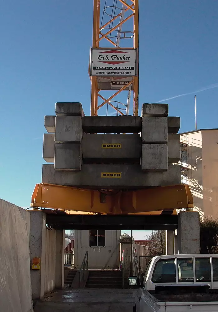 Turmkran mit Betongewichten und Firmenlogo „Seb. Pauker Hoch- und Tiefbau“, aufgebaut über einer Zufahrt