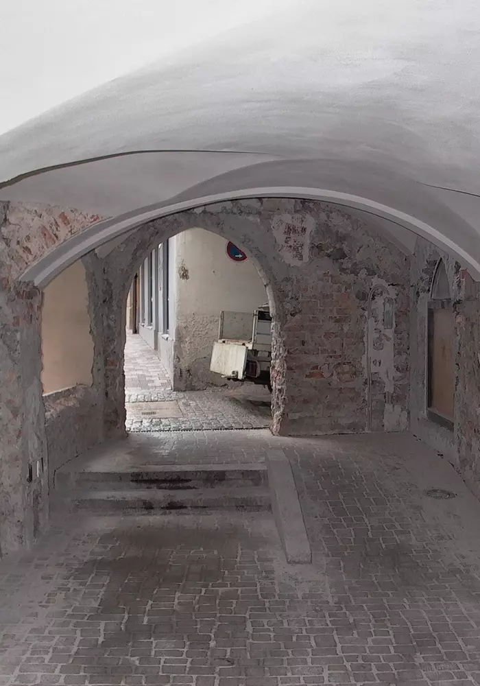 Blick durch alten Gewölbegang mit Backsteinmauern, Stufen und geparktem Kleintransporter im Hintergrund.