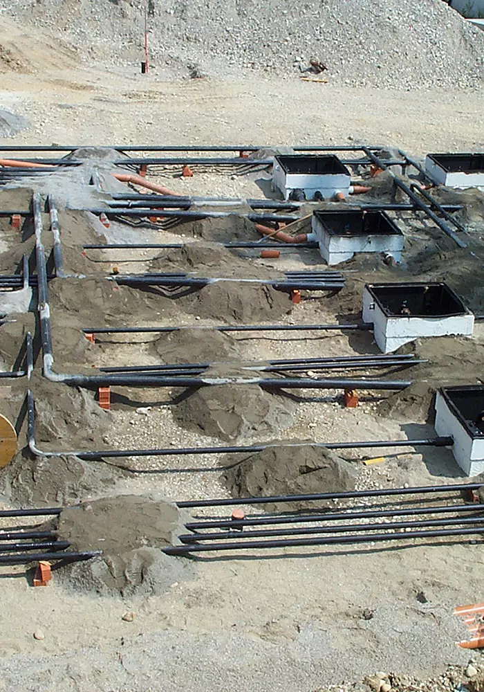 Baustelle mit verlegten Versorgungsleitungen und mehreren Revisionsschächten im Erdreich.