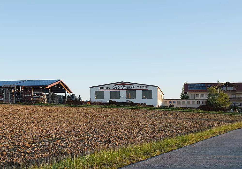 Betriebsgelände der Firma Seb. Pauker mit Lagerhalle, Bürogebäude und Feldern im Vordergrund.