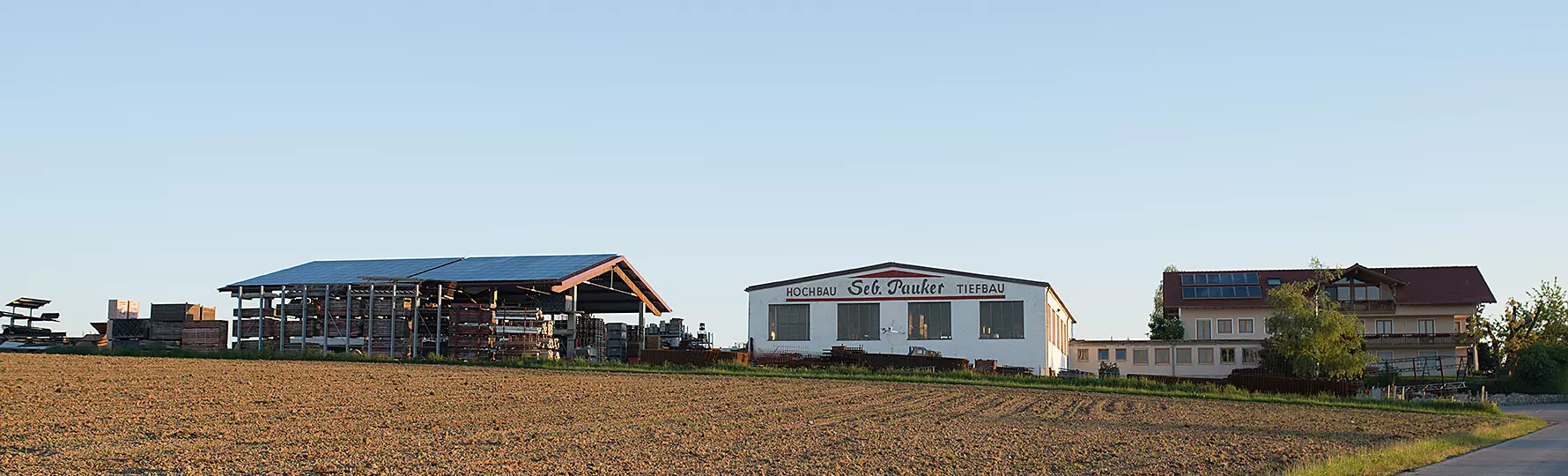 Betriebsgelände der Firma Seb. Pauker mit Lagerhalle, Bürogebäude und Feldern im Vordergrund.