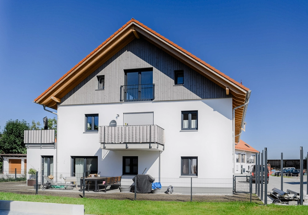 Mehrfamilienhaus mit Balkon und Holzverkleidung im Giebelbereich