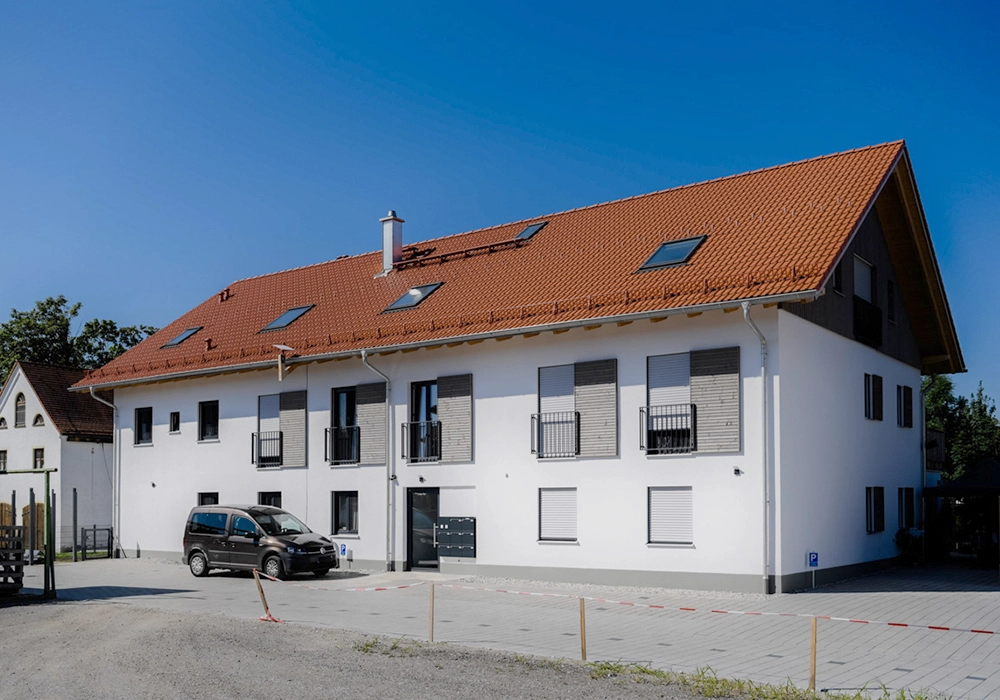 Mehrfamilienhaus mit Eingangsbereich und Stellplätzen vor der Fassade