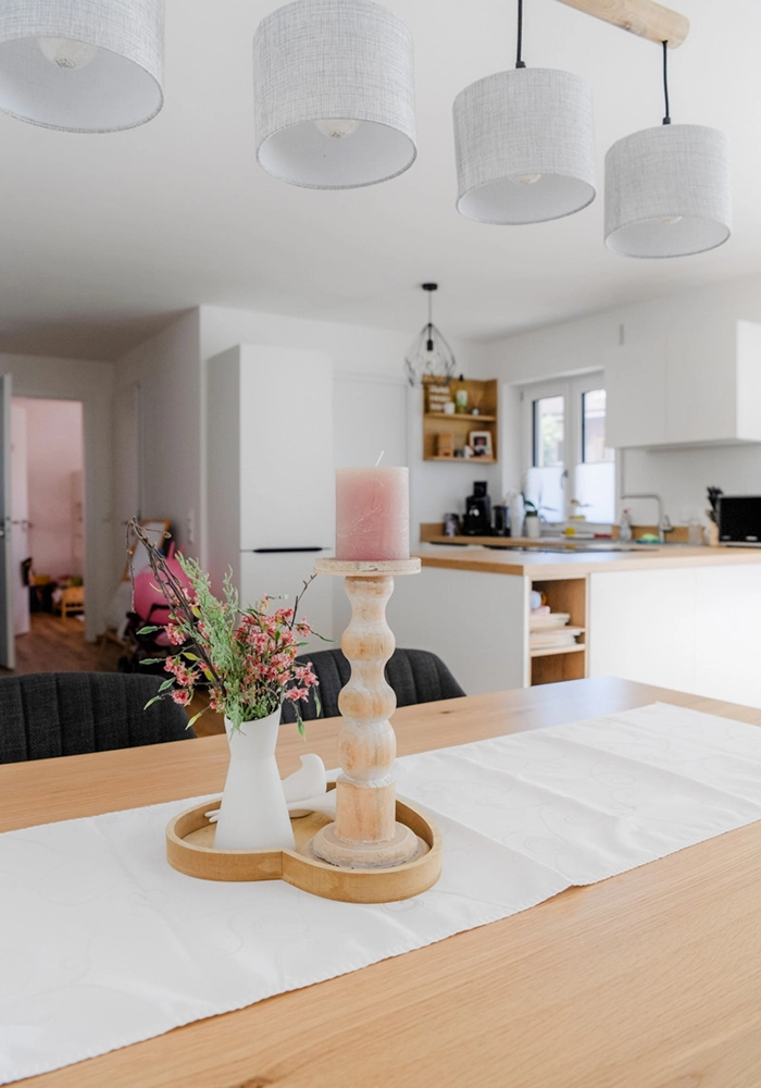 Esstisch mit Dekoration im offenen Wohnraum mit Küche im Hintergrund