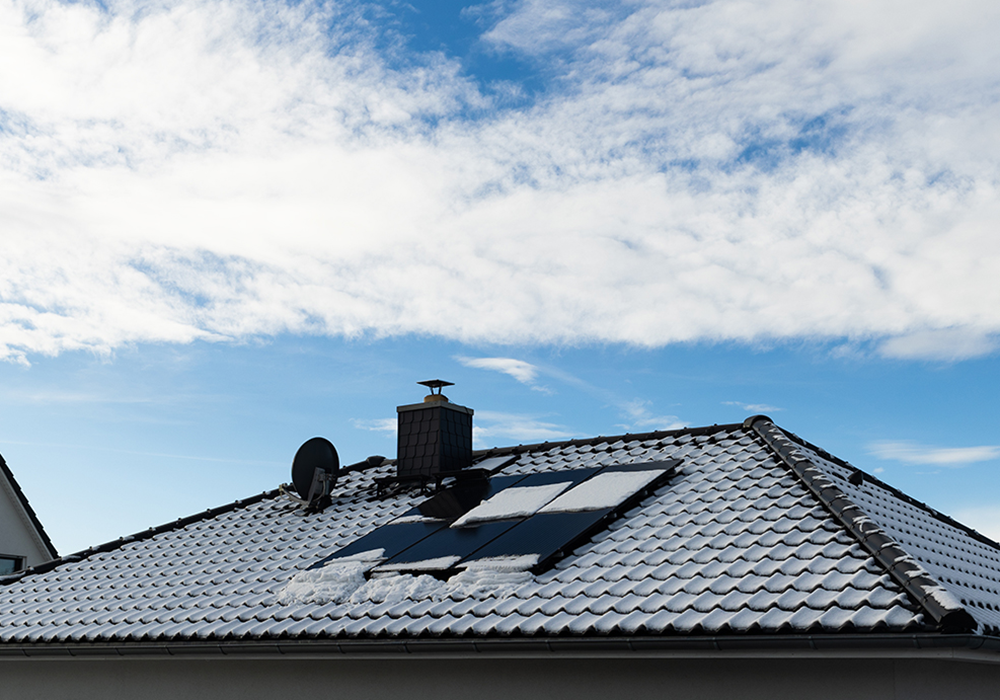 Hausdach mit Photovoltaikanlage im Winter – nachhaltige Energiegewinnung beim energieeffizienten Hausbau.