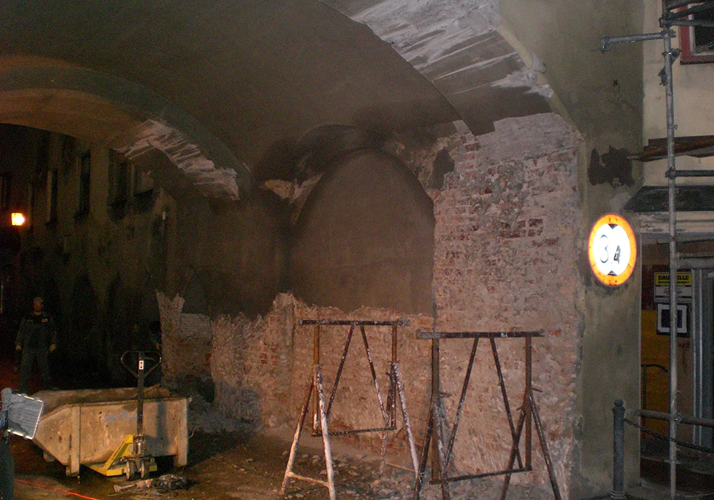 Freigelegtes Ziegelmauerwerk im Torbogen während nächtlicher Sanierungsarbeiten am historischen Bauwerk