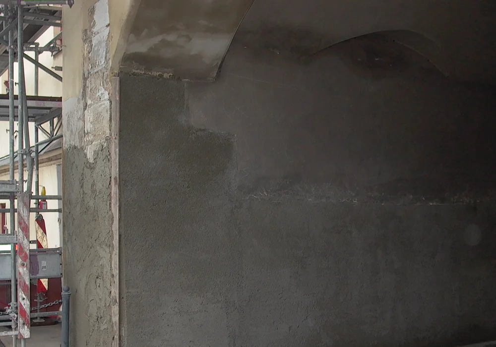 Frisch aufgetragener Sanierputz im Torbogenbereich während Restaurierungsarbeiten am Brucktor