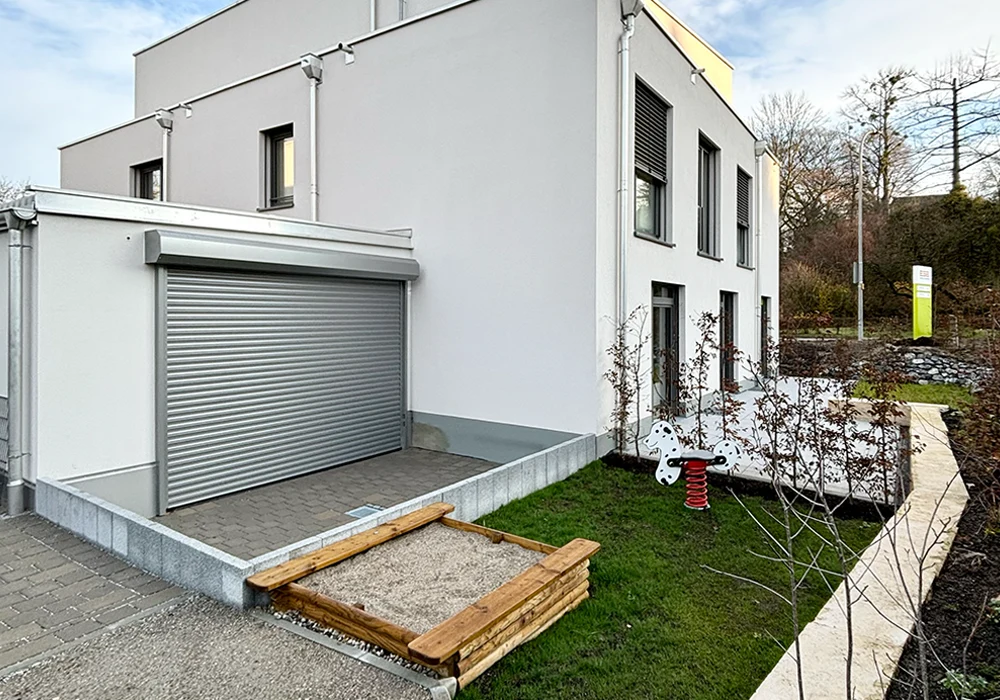 Rückansicht eines Wohn- und Bürogebäudes mit Terrasse und Spielplatz