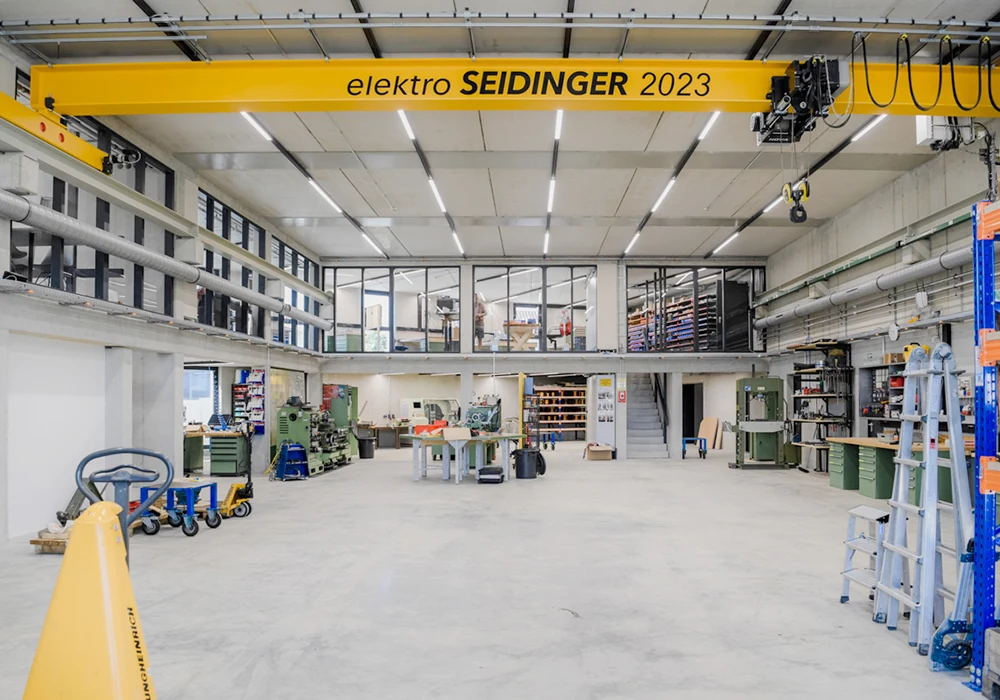 Große Werkhalle mit Arbeitsplätzen, Maschinen und Hallenkran im Gewerbebau