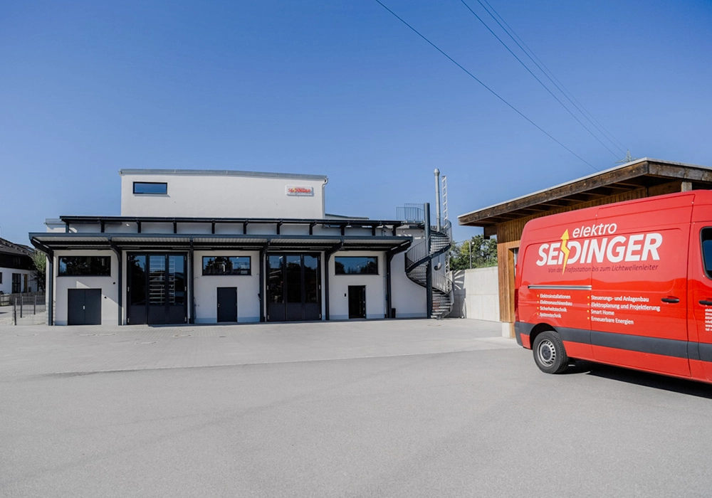 Gewerbegebäude mit Hallentoren und Firmenfahrzeug auf großer Hoffläche