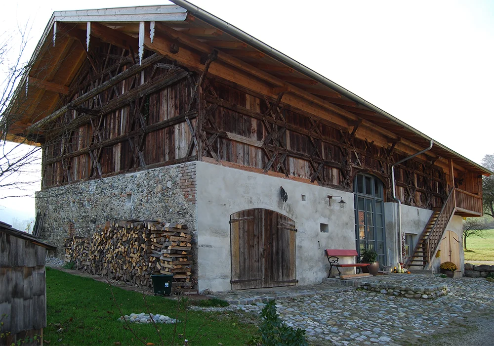 Sanierter Bauernhof mit Holzfassade, Natursteinmauerwerk und neuer Außentreppe im Hof